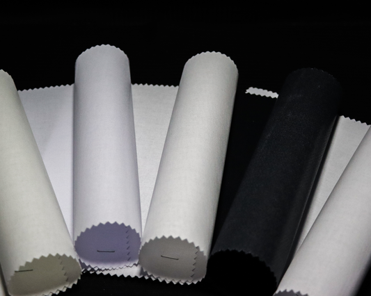 Rolls of IF2777 fabric interlining in various colors on a black background