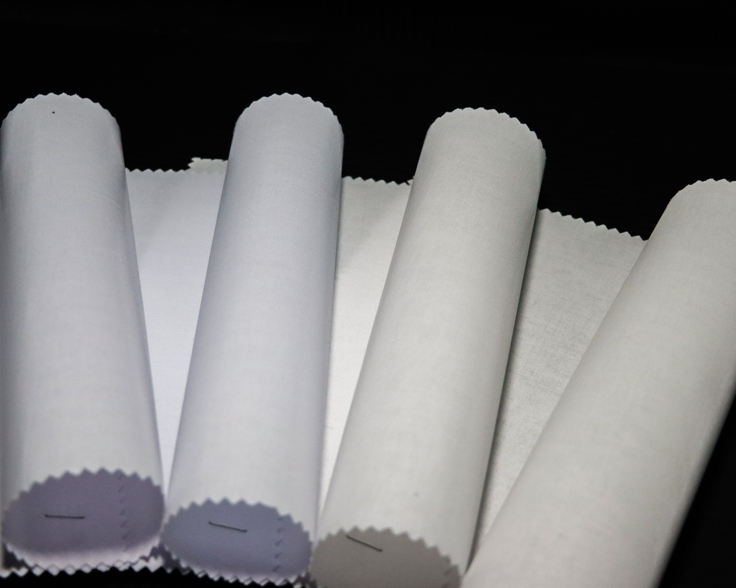 fusible interlining fabric rolls of shades of white on a black background
